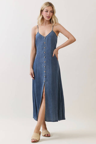 Woman wearing a blue denim dress with a button front and slit on a white background