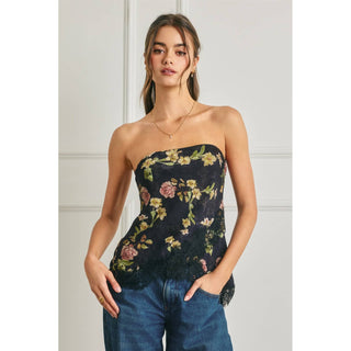 Woman wearing a strapless floral top and jeans against a light background