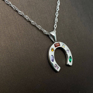 Silver horseshoe pendant necklace with colorful stones on a brown background
