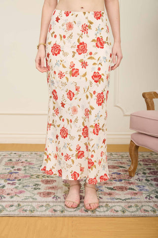 Person wearing a floral skirt standing in a room with a patterned rug and chair.