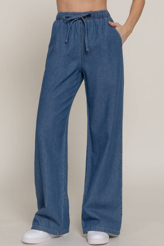 Blue denim pants worn by a person on a beige background