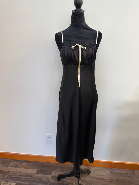 Black dress on a mannequin against a plain wall.
