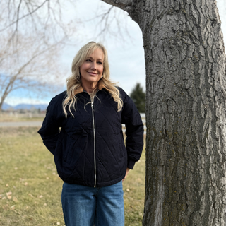 Woman standing next to a tree in an outdoor setting
