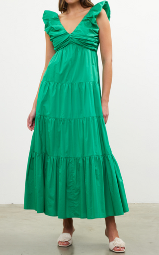 A model wearing a green V neck shirred maxi dress with ruffled sleeves and a pleated skirt.