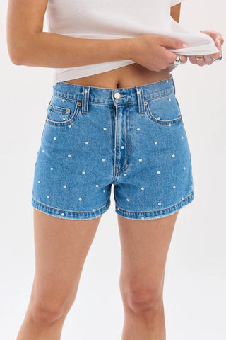 Blue denim shorts with white polka dots worn by a person on a white background