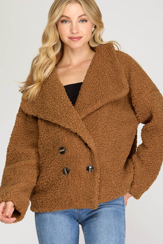 Woman wearing a brown teddy coat with a plain background
