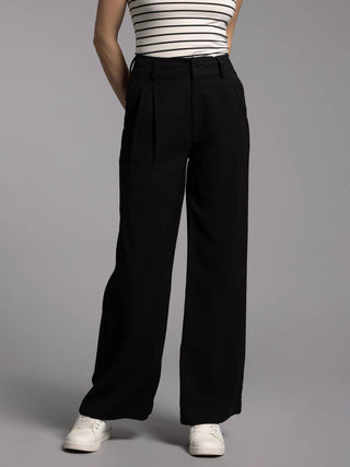 Person wearing black wide-leg pants and a striped top on a gray background