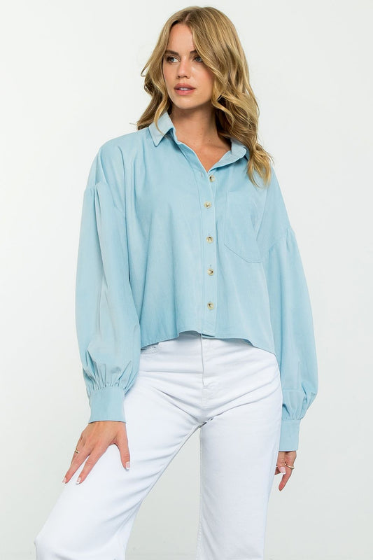 Woman wearing a light blue blouse and white pants on a white background