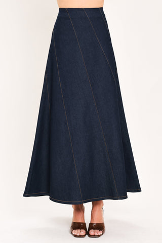 Dark indigo denim maxi skirt with diagonal seams and flared A-line silhouette on model