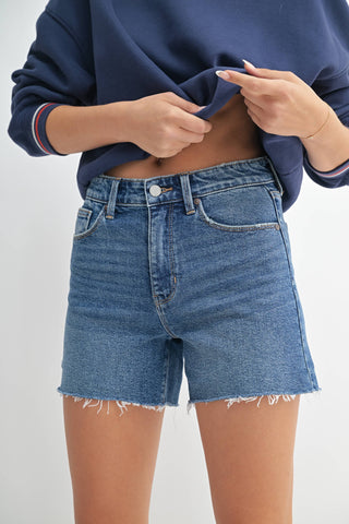 Person wearing blue denim shorts and a navy sweater on a white background