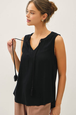 Woman wearing a black sleeveless top against a plain background