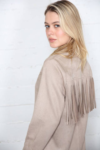 Woman wearing a beige fringe jacket against a white background