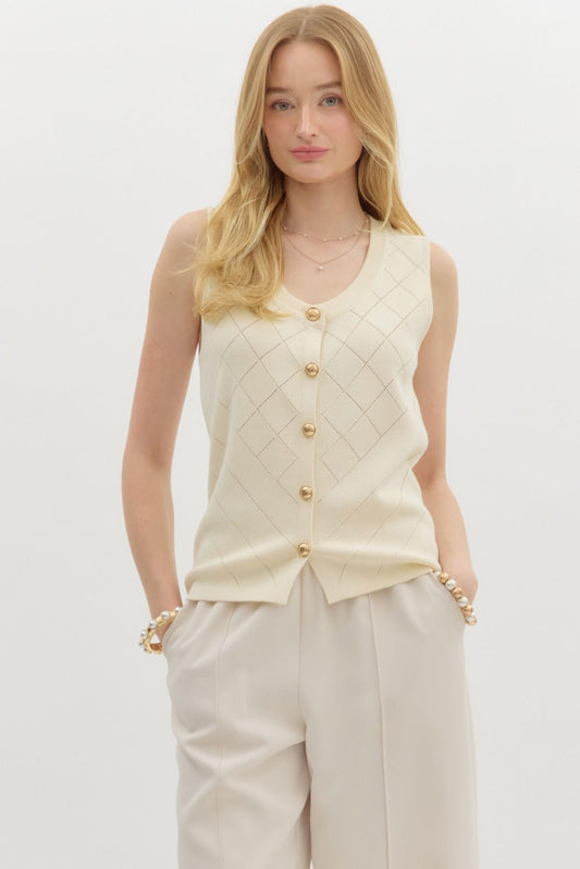 Woman wearing a cream-colored sleeveless cardigan with gold buttons on a white background
