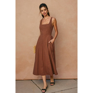 Woman wearing a brown dress against a beige wall