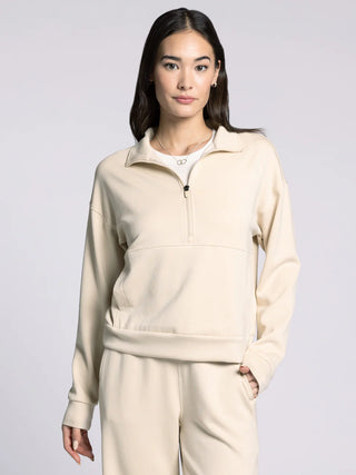 Woman wearing a beige tracksuit against a plain background