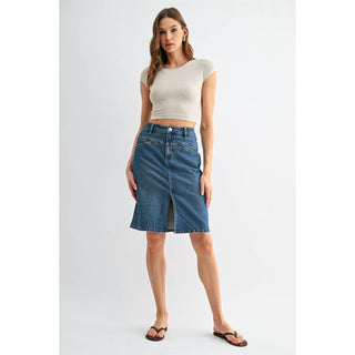 Woman wearing a white crop top and blue denim skirt on a light gray background