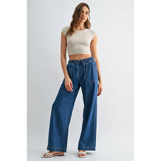 Woman wearing a white crop top and blue jeans on a light gray background