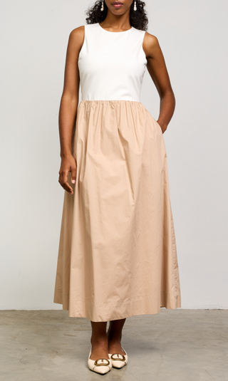 Woman wearing a white top and beige skirt against a plain background