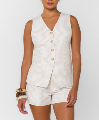 Woman wearing a white ribbed button-up sleeveless top and shorts on a light gray background