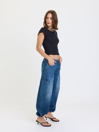 Model wearing wide-leg cargo harem jeans with large patch pockets and gathered hem