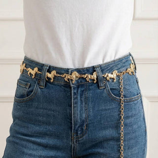 Gold horse figure chain belt worn over blue denim jeans with white top