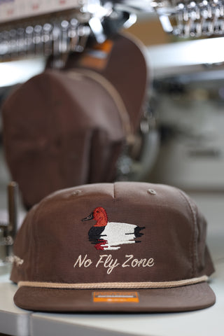 Brown cap with duck design and 'No Fly Zone' text on a rack.