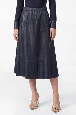 Model wearing a navy PU leather A-line midi skirt with elasticized waist and panel seam detailing