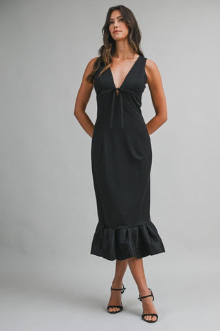 Woman wearing a black dress with a ruffled hem on a gray background
