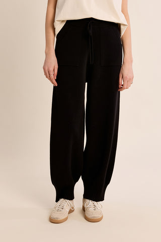 Black wide-leg knitted pants with drawstring waist, front pockets, and ribbed cuffs