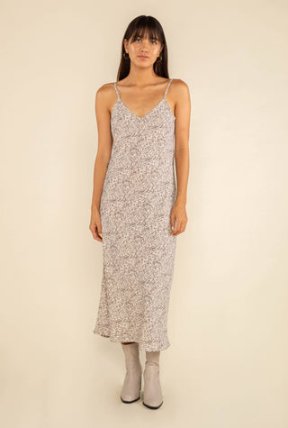 Woman wearing a floral slip dress against a beige background