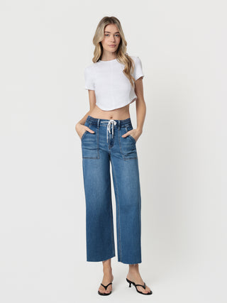 Woman wearing blue jeans and a white crop top on a white background
