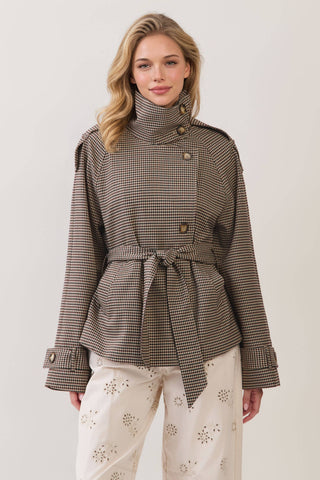 Model wearing a belted houndstooth plaid cropped trench coat with high neck and gold buttons