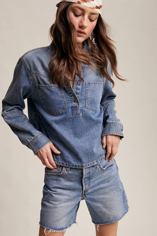 Woman wearing a denim outfit with a jacket and shorts on a plain background