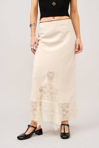 Person wearing a black top and white lace skirt on a white background