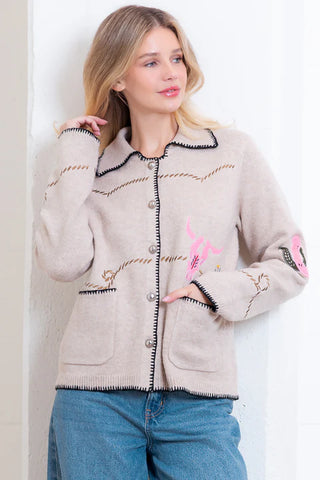 Woman wearing a beige cardigan with decorative patterns on a white background