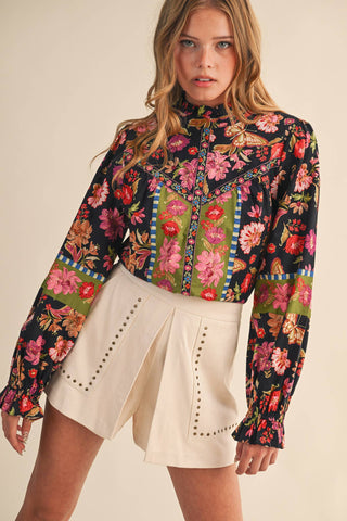 Woman wearing a colorful floral blouse with a plain background