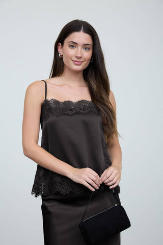 Woman wearing a black lace-trimmed top against a plain background
