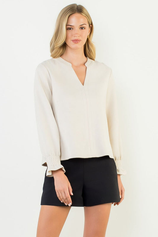 Woman wearing a white blouse and black shorts on a white background