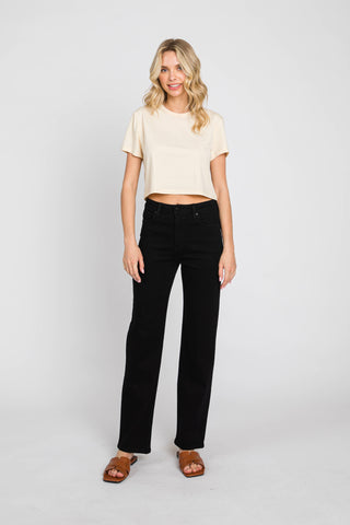 Woman wearing a beige top and black pants on a white background