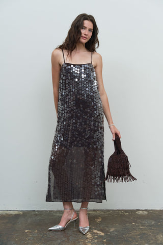 Model wearing a dark brown sequin spaghetti strap slip midi dress with silver heels