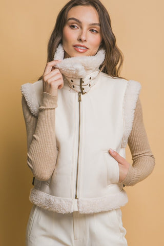 Woman wearing a white puffer vest with fur trim against a beige background