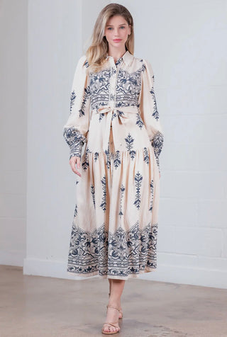 Woman wearing a long, patterned dress against a plain background