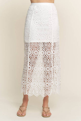 A white midi skirt with a geometric floral/sun pattern lace design, scalloped hemline, and a back zipper.