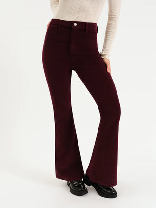 Maroon flared pants worn with a beige sweater on a white background