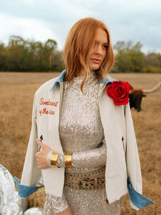 Woman in a sparkly dress with a red flower in a field