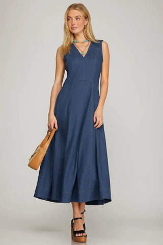 Woman wearing a blue dress holding a brown bag on a plain background