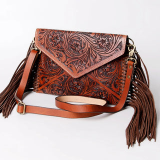 Brown leather handbag with intricate patterns and fringes on a white background