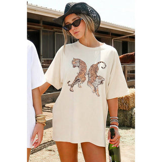 Woman wearing a white t-shirt with tiger designs outdoors.