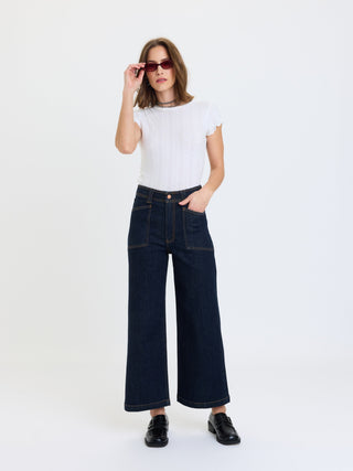 Model wearing high-rise wide-leg ankle jeans with patch pockets and contrast stitching