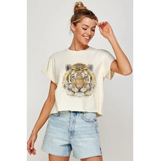 Woman wearing a t-shirt with a tiger graphic and denim shorts on a plain background